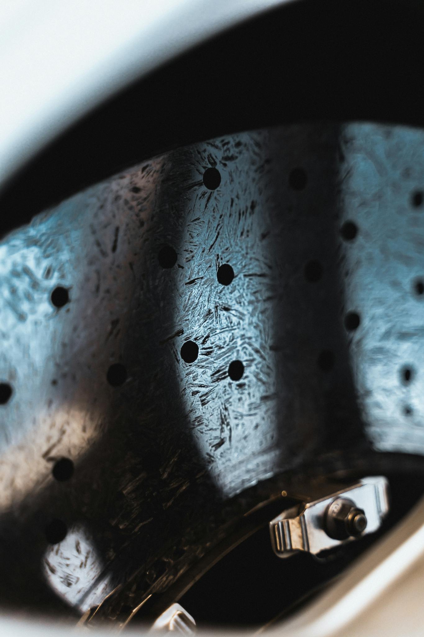 Detailed view of a metallic car brake disc featuring holes and a shiny surface, emphasizing precision engineering.